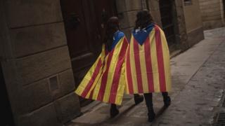 Two young girls draped in a Catalan pro-independence flag walk on October 2, 2017