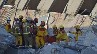 Rescuers bring out an eight-year old girl survivor to waiting personnel after she was rescued from the rubble at the Wei-Kuan complex which collapsed in the 6.4 magnitude earthquake, in the southern Taiwanese city of Tainan on February 8, 2016. T