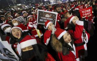 People wearing Santa Claus costumes shout during a rally calling for South Korean President Park Geun-hye to step down in Seoul, South Korea, on 24 December, 2016.