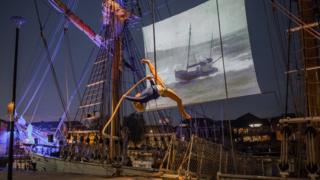 The Kaskelot docked up with a film showing on the ship's sails