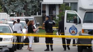 People watch from their front door as police stand at a crime scene where three pople have died in an incident involving a crossbow, according to local media reports in the Scarborough suburb of Toronto, August 25, 2016. REUTERS/Mark Blinch