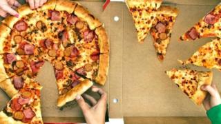 Unas personas tomando pedazos de una pizza