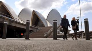 Couple walk past bollards at Sydney opera house