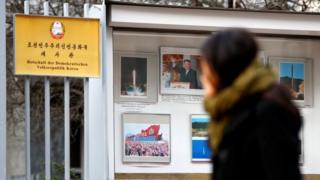 A person walks past while watching photographs outside the compound of the North Korean embassy in Berlin, Germany, 1 December 2017.
