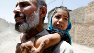 A man displaced by fighting between Iraqi forces and Islamic State militants carries his daughter in Mosul's Zanjili district (7 June 2017)