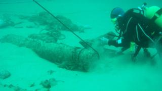Diver examining cannon on Alderney Elizabethan wreck on seabed