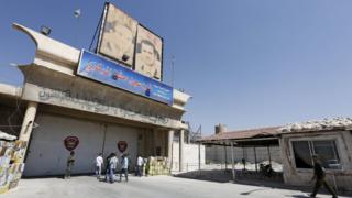 Syrian security personnel and journalists stand at the entrance to Damascus's central prison (23 August 2015)