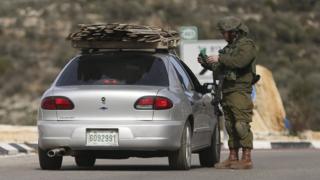 Israeli soldier checks identity papers of a driver at a checkpoint leading to the West Bank city of Ramallah (1 February 2015)
