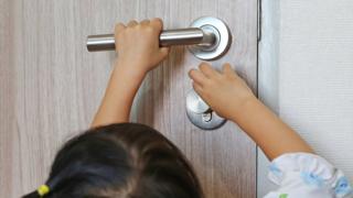 Young child trying to open a heavy door
