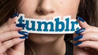 Mujer sostiene sobre la boca un molde de letras que dice Tumblr.