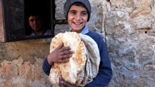 Boy holds bread in Aleppo province, Syria