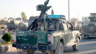 An Afghan policeman travels on a pick up truck in the embattled city of Tarin Kot