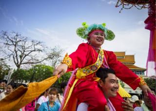 A Shan boy is carried around the Three Kings Monument in Chiang Mai during an afternoon procession of Poy Sang Long participants.