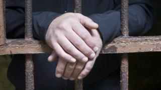 Mãos de um homem atrás das grades