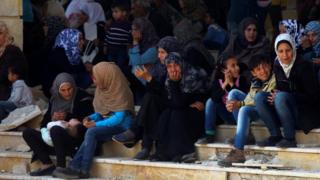 People, who were evacuated from the two rebel-besieged Shiite villages of Foah and Kefraya, wait at insurgent-held Rashidin, to travel to government-controlled Aleppo