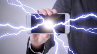 Una persona que sostiene un teléfono, del cual salen rayos