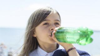A young girl drinks a fizzy drink