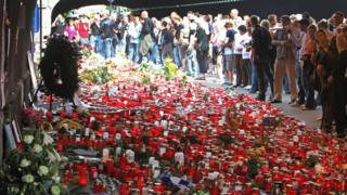 This file photo taken on July 31, 2010 shows people mourning in front of a makeshift memorial of candles and flowers at the site where the 21 Love Parade victims died in Duisburg, western Germany.