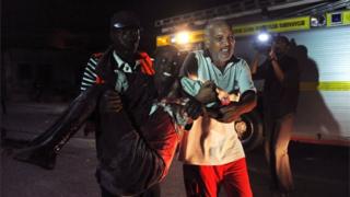 Residents help a man wounded during an attack in the center of Mogadishu on February 26, 2016
