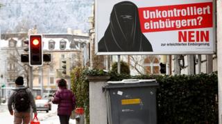 Orang berjalan dekat poster "Komite melawan jalan mudah mendapat kewarganegaraan" yang ada di dekat stasiun kereta Hauptbahnhof, Zurich, 11 Januari 2017