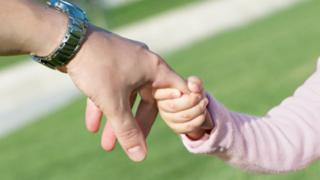 Child and adult hold hands