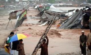 People gather around their shops after they were swept away by flash floods triggered by heavy rains