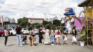 Fila para a bilheteria do circo e, ao fundo, boneco de palhaço