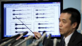 Japan Meteorological Agency's earthquake and tsunami observations division director Yohei Hasegawa points at a graph of seismic data