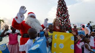 Haka kuma wannan mutumin da ya yi shiga irin ta Santa ya tsaya kusa da mai dakin shugaban Ivory Coast's first lady Dominique Ouattara (wacce ke tsakiya) da kuma kananan yara a fadar shugaban kasar da ke Abidjan a yayin da ake shirye-shiryen bikin Kirsimeti.