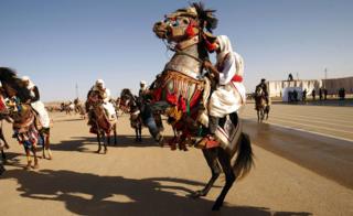 Libyan dressed in traditional costumes attend a military parade in the eastern city of Benghazi on May 7, 2018, during which Libyan strongman Khalifa Haftar announced a military offensive to take from "terrorists" the city of Derna, the only part of eastern Libya outside his forces" control.