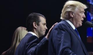 Donald Trump, Jr places a hand on the shoulder of his father, Donald Trump, during a rally on the final night of the 2016 US presidential election