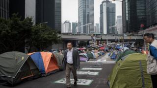 Occupy Central co-founder Benny Tai Yiu-ting (L) walks past tents at a pro-democracy protest site set up on a highway in the Admiralty district of Hong Kong on 4 November 2014