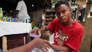 A nail artist fixes client's nail on Valentine's Day at Wuse market in Abuja, Nigeria 14 February 2018