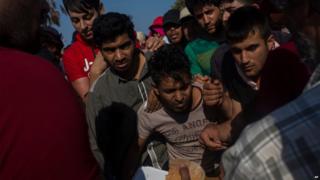 Migrants scuffle each other to get a meal served by volunteers on the Greek island of Kos Wednesday, July 15, 2015.