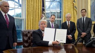 President Donald Trump holds up an executive order