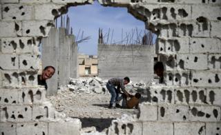 Boys play near remains of war-damaged buildings in the rebel-held Damascus suburb of Douma (19 March 2016)
