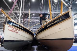A member of staff polishes a Cornish Crabber sailing boat at the London Boat Show in Docklands, east London.