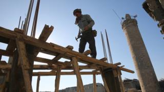 عامل عراقي ينصب حمالات خشبية