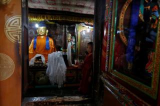 A young Buddhist monk stands inside Thiksey monastery, Ladakh, India.