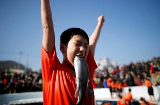A boy reacts after catching a trout.