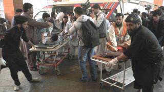 Pakistani security personnel and volunteers move victims injured in a suicide bombing to a hospital in Peshawar on 7 March 2016, after an attack on a court complex in the town of Shabqadar