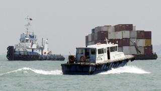A shipping services boat passes a barge in Singapore