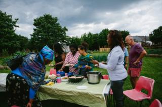 Participants and volunteers share out food on a table outside
