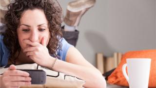 Mujer con expresión de sorpresa mirando el teléfono