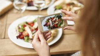 Woman taking photo of meal on phone
