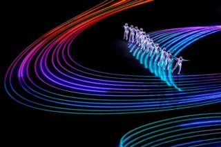 Artists perform around projected lines of coloured light