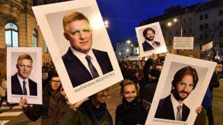 Protesters carry signs depicting Prime Minister Robert Fico, left, and interior minister Robert Kalinak