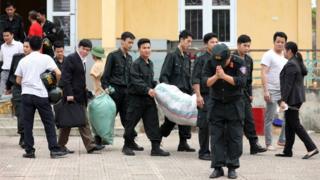 A police officer bows as he walks out of the Dong Tam commune on the outskirts of Hanoi, Vietnam, with 19 hostages who were originally held in a land dispute, 22 April 2017