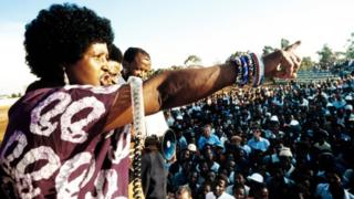 ውርይቲ ተቓላሲት ዊኒ ማዲኪዜላ ማንዴላ፡ ደሓር ድማ ሰበይቲ ኔልሰን ማንዴላ፡ ኣብ ከተማ ካጊሶ ንህዝቢ መደረ እንትተስምዕ 13 ሚያዝያ 1986 ኣቆፃፅራ ኣውሮጳውያን ዝተወሰደ ምስሊ
