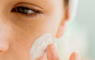 Mujer aplicándose una crema en la cara.